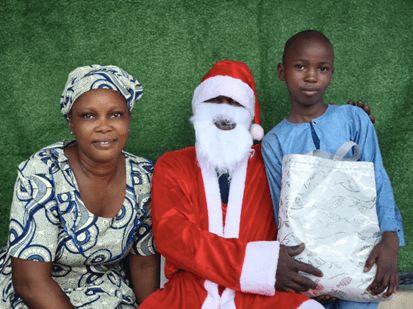 Three Nigerian girls standing next to each other. The girl in the middle puts her arms around the others.